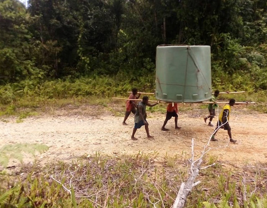 Youths carry a tank from the shore to the local primary school ©Albert Aisim, Anglican Church of PNG