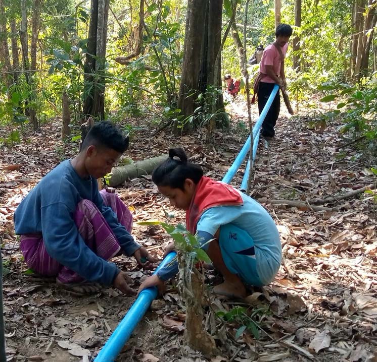 Myanmar villagers laying water pipes through a remote forested area. © CPM.