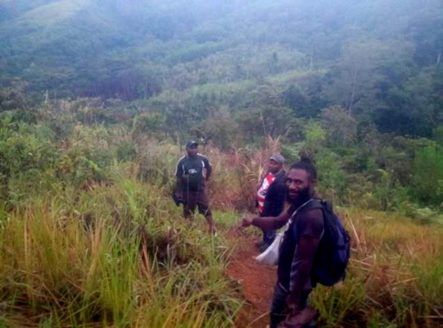 The visitors (Morrison is in the middle of the three walkers) left at three in the morning to walk into the village. ©Morrison Wiam, Anglicare PNG