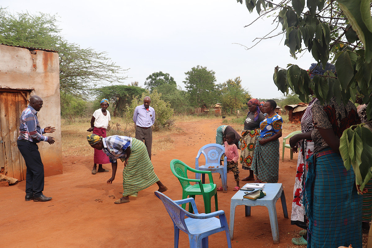 Tila Ngukune Self-Help Group demonstrate with stones and sticks the progress they have made since the project began. © ADSE. Used with permission.