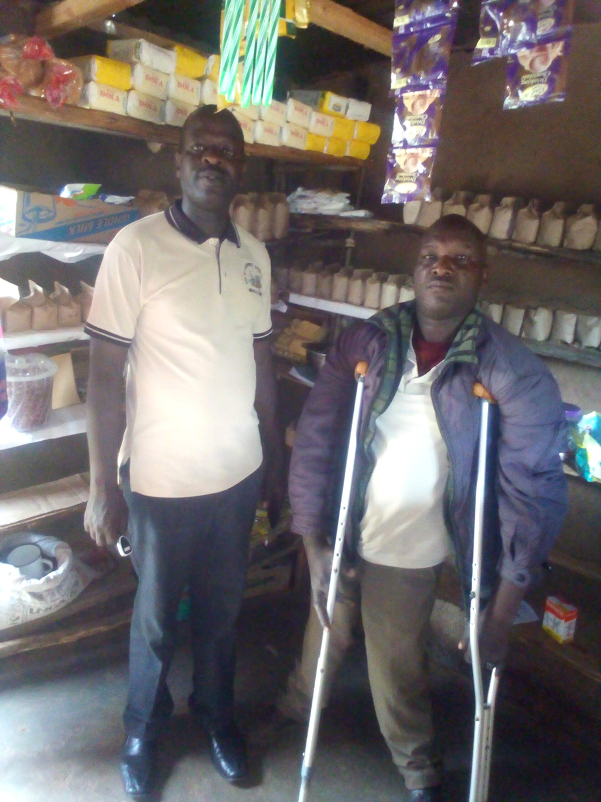 Gabriel’s Parish Vicar, Rev’d Kennedy Mirmet (left), pays him a visit at the shop. © Diocese of Eldoret. Used with permission.