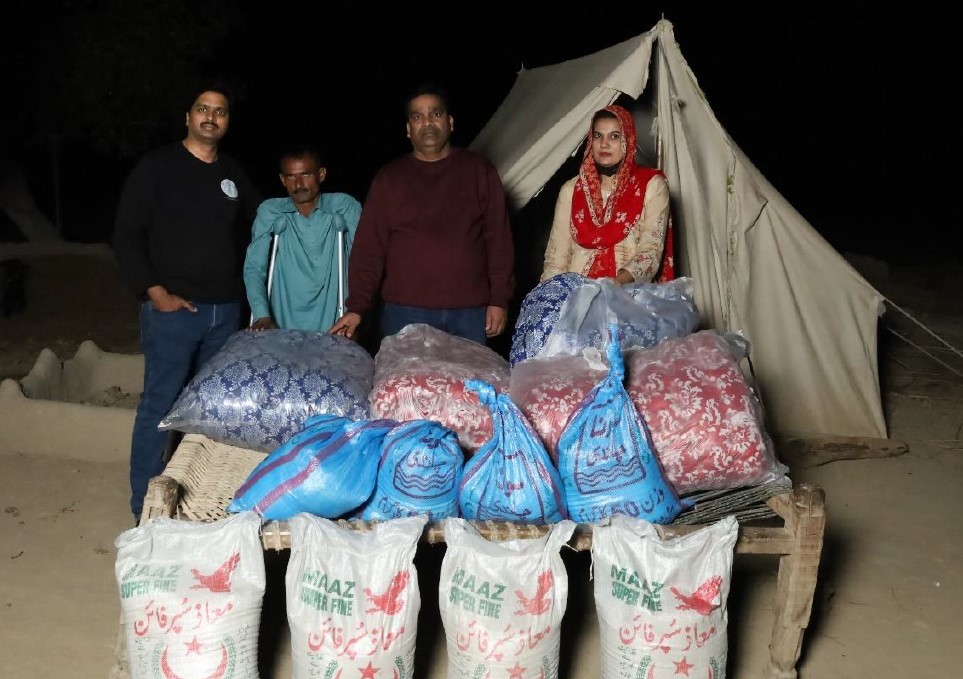 Church workers distributing food and quilts to flood-affected villages, including Mr Shafi, second from left © Church of Pakistan. Used with permission.