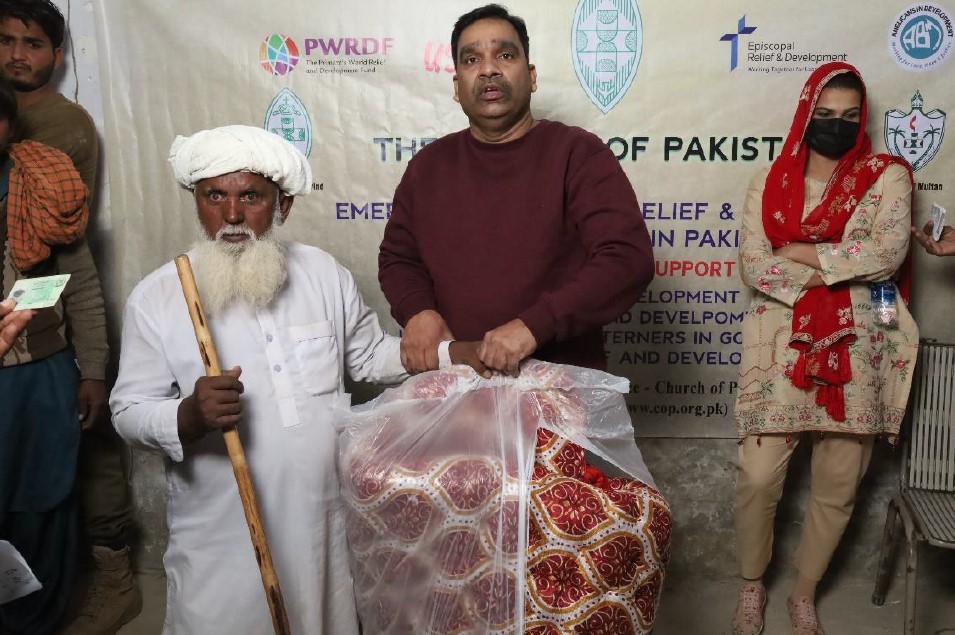 The Church of Pakistan hands a quilt to an elderly man. © Church of Pakistan. Used with permission.