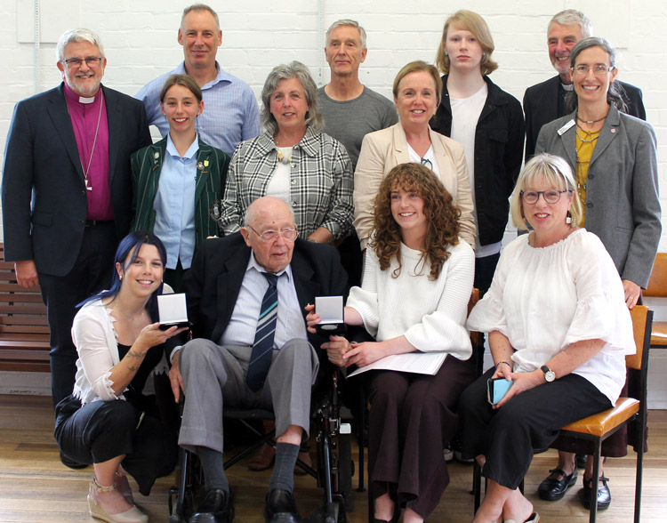 Rev’d Brian (front, second from left) sits with his family as they admire his Coaldrake award. The Rt Rev’d Richard Condie and Meagan join them for the photo ©ABM