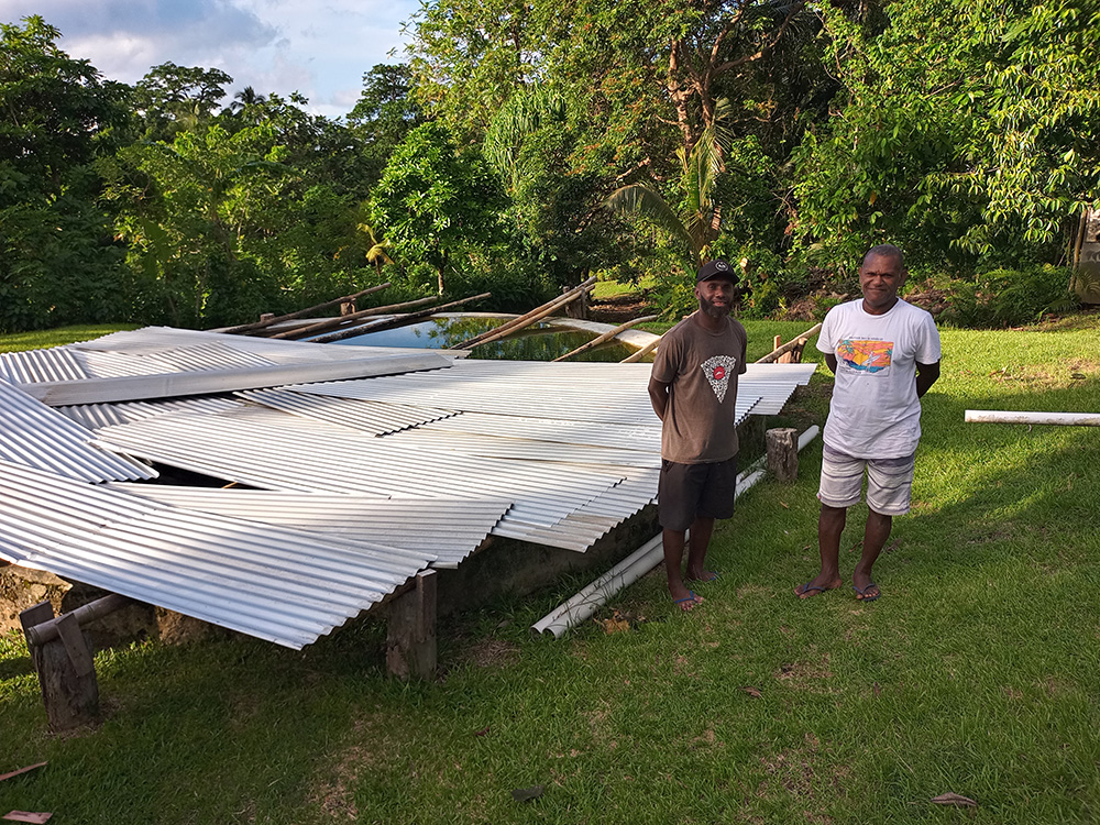 Edgell and Bradley with the water tank constructed at Saranabuka. © Terry Russell, AID.