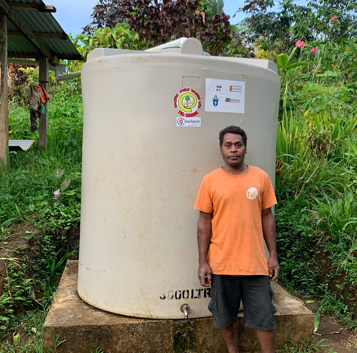 Fr Stanley Tabi with newly installed water tank in Enkul, Pentecost. © ACOM Vanuatu. Used with permission.