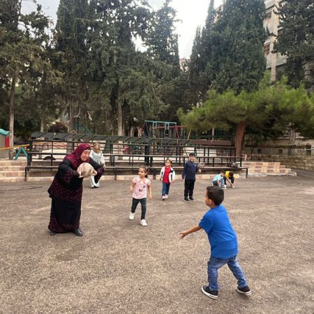 Young students play a ball sport with their teachers in the school’s outdoor courtyard. © HLID. Used with permission.