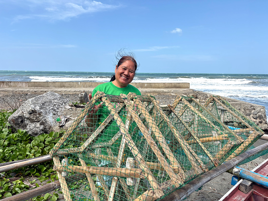 Rufina, a member of the Songcolan Seashore Livelihoods Association, with the new boat and crabnets she built. Her income is more secure thanks to participating in Receivers to Givers with ECARE © ABM/Meagan Schwarz.