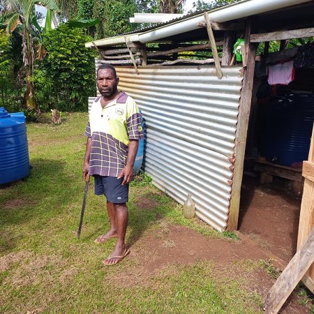 Fr Willie Loli, parish priest at Revelco on Santo Island in Vanuatu, with two 500-litre water tanks (one in the shed), both intended for use by people living with disabilities. © ABM/ Terry Russell.