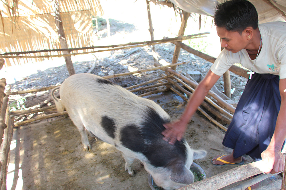 Win proudly pats the pig he received in 2015, funded by ABM AID.