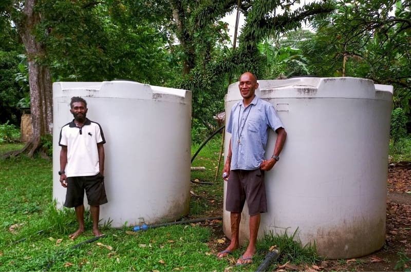 Local Area Administrator Keithson Ture Garae (left) with Anglican priest Fr Andrew Tari (right). Together, they mobilised the community to connect these tanks to a well and communal taps. © Terry Russell, ABM AID