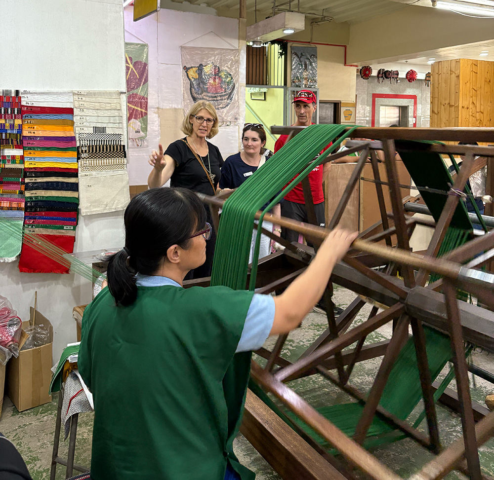 Bishop Sarah and Juliana watching an Easter Weaving Room weaver at work © ABM Meagan Schwarz.