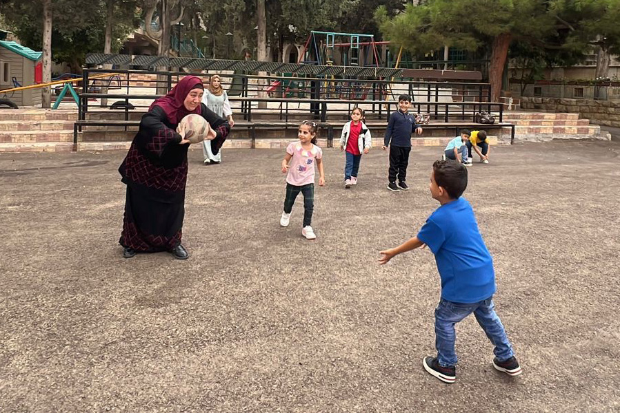 Young students play a ball sport with their teachers in the school’s outdoor courtyard. © HLID. Used with permission.